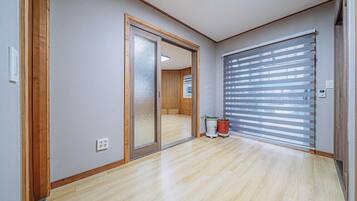 A hallway with a sliding glass door leading to a room, a potted plant, and a window with blinds.