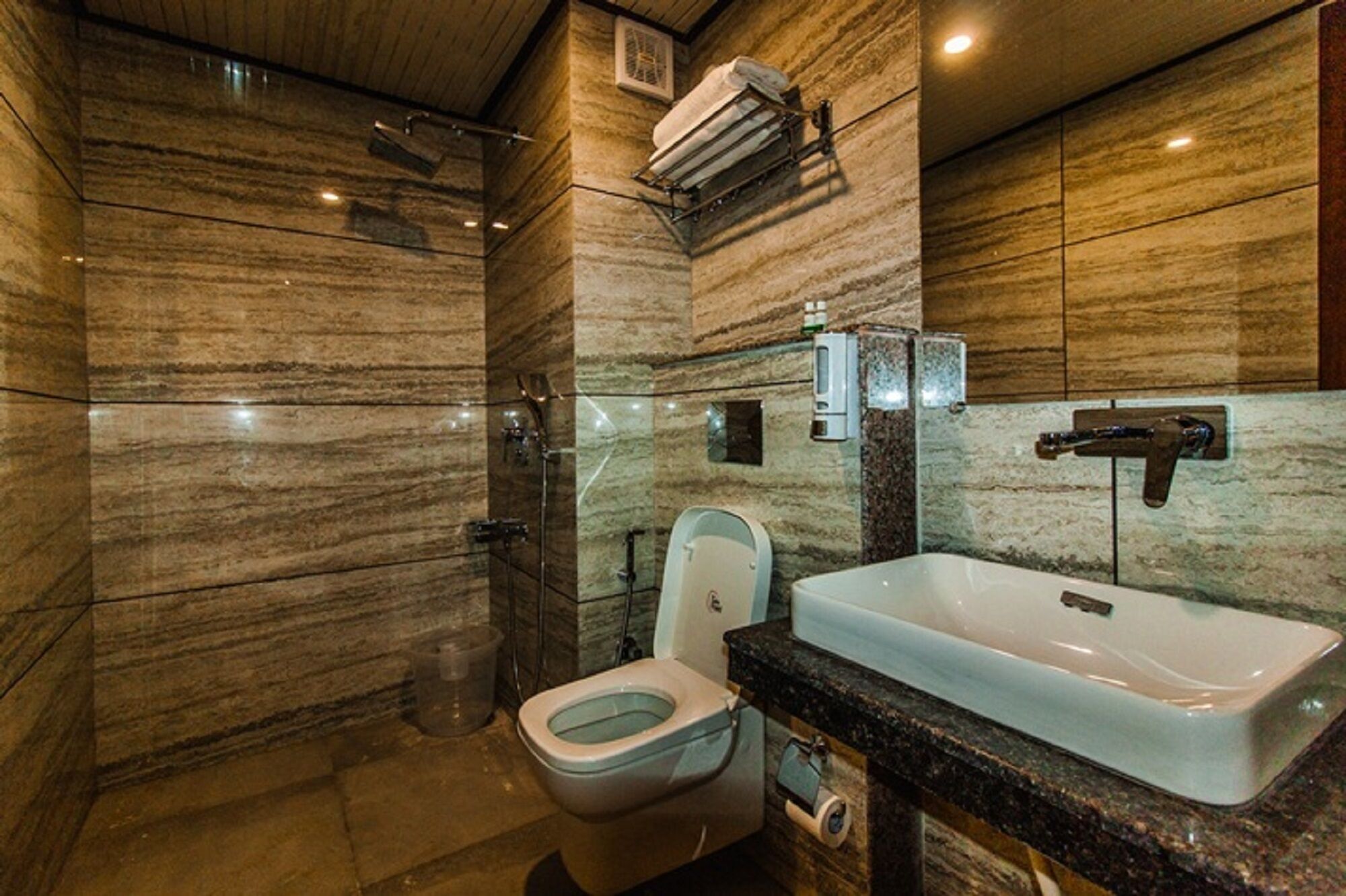 A modern bathroom with a marble wall, a large sink, and a toilet.