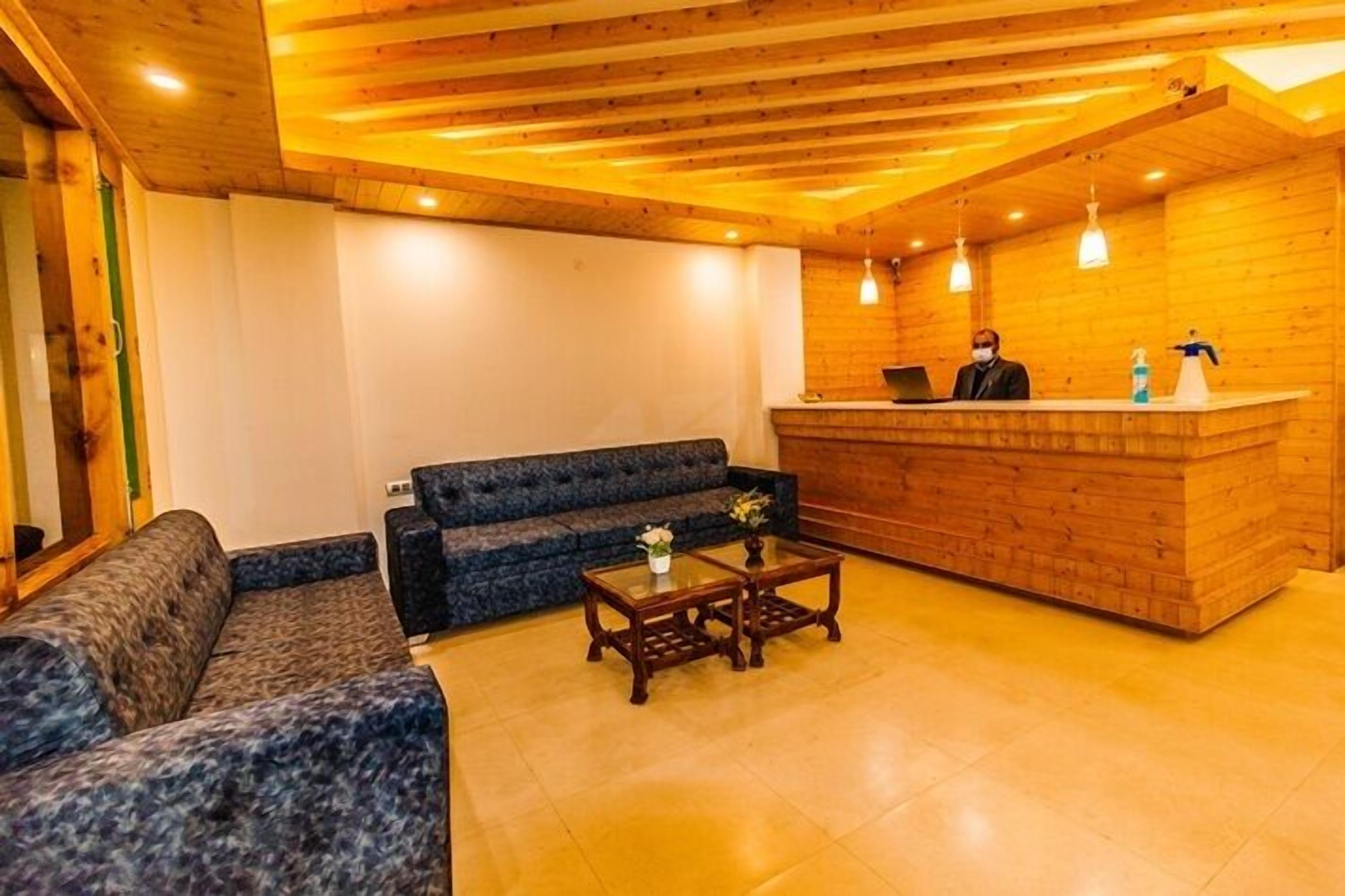 Un área de recepción con un mostrador de madera, un sofá azul y una pequeña mesa de centro con un jarrón.