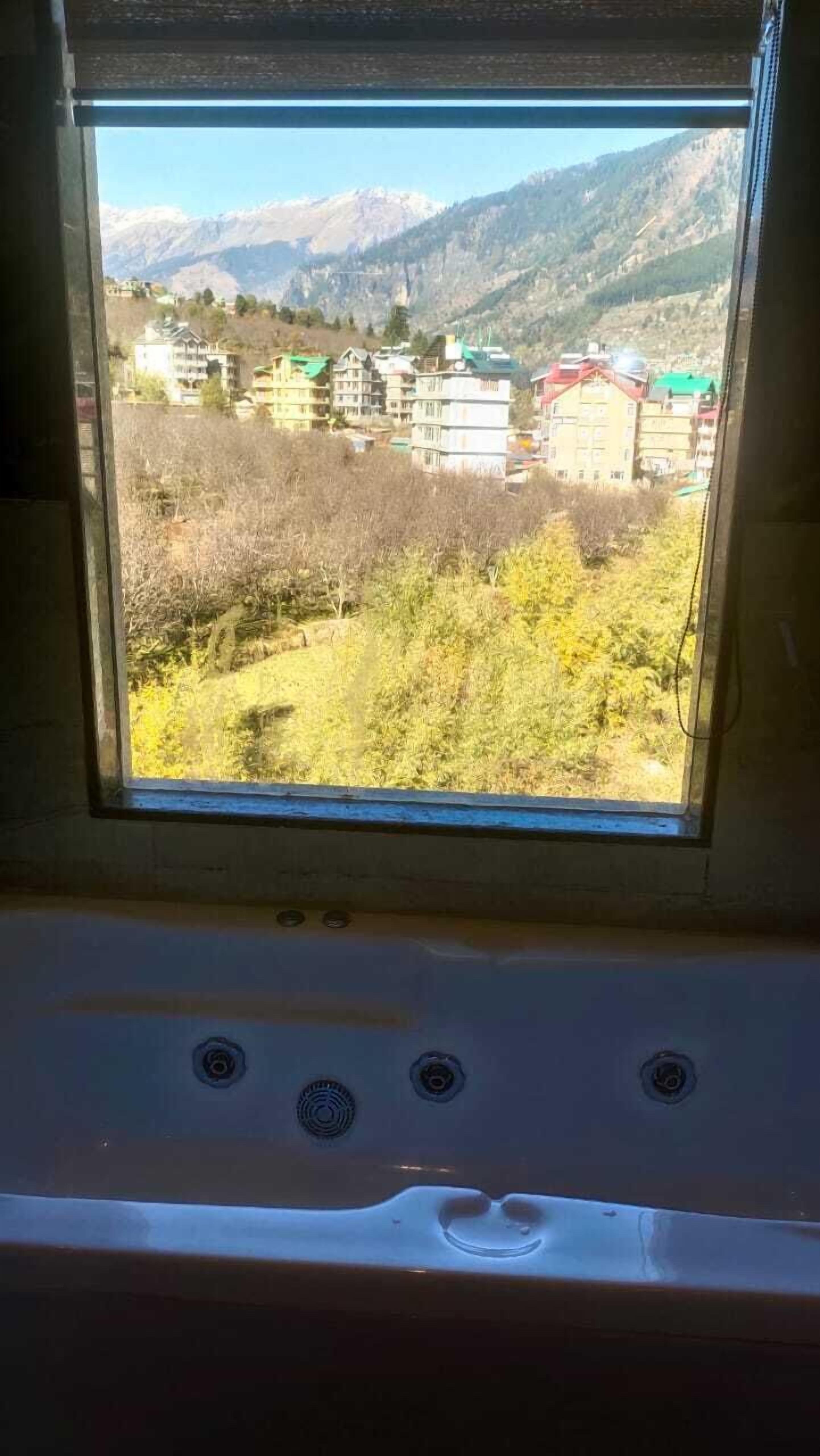 A window with a view of a mountainous landscape and buildings.