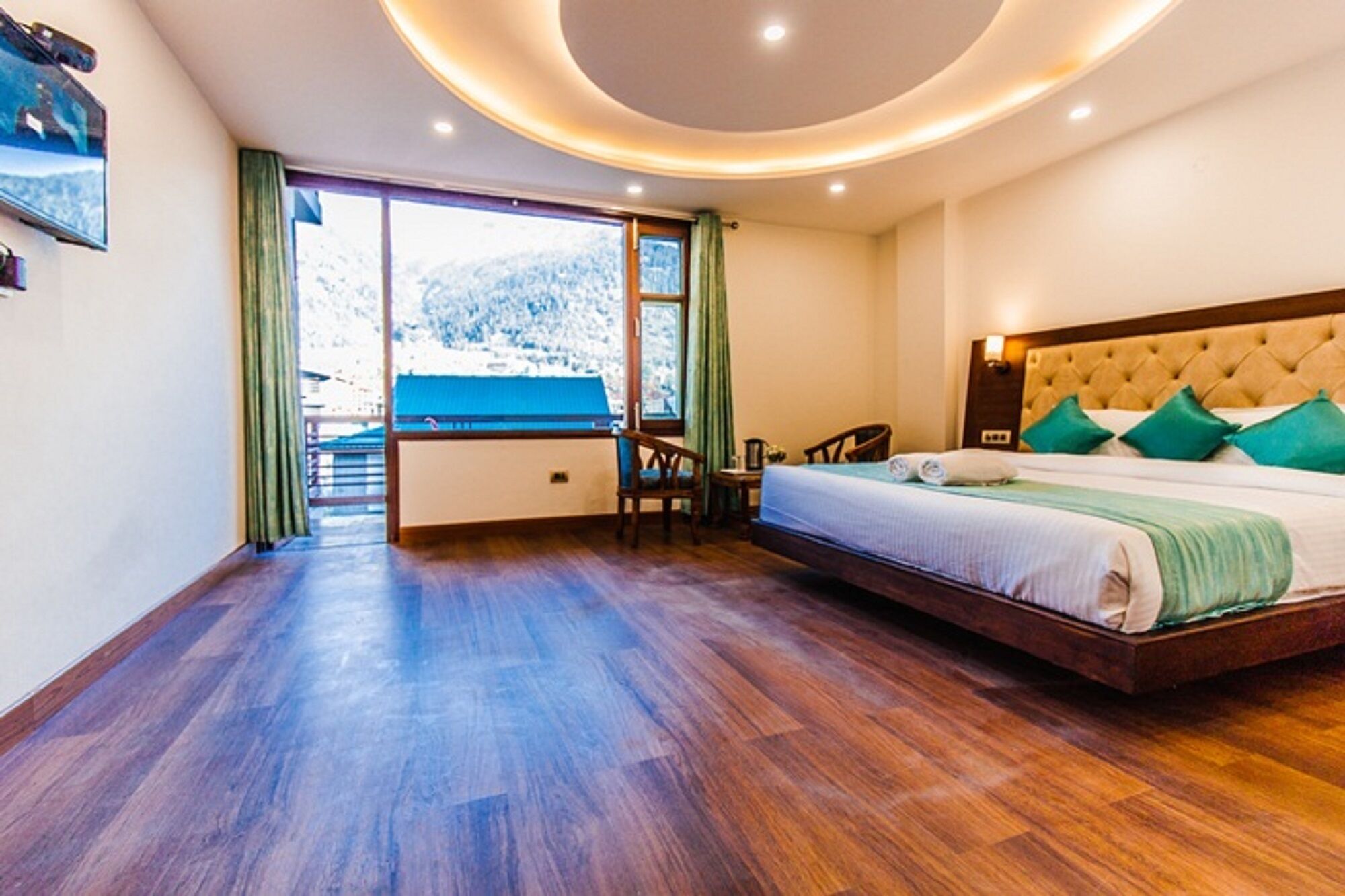 Une chambre avec un grand lit, une vue sur un paysage enneigé par une porte coulissante et un plancher en bois.