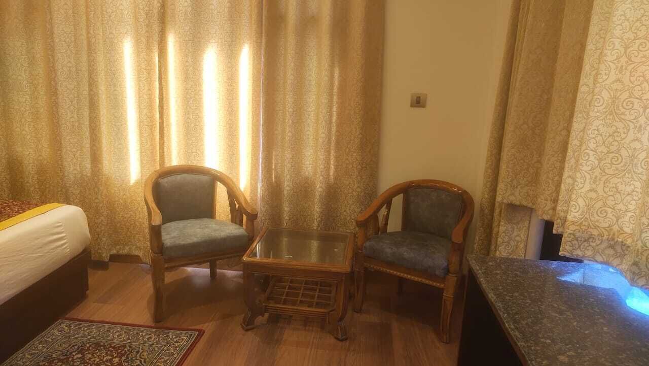 A hotel room with a bed, two armchairs, a small glass table, and a sofa.