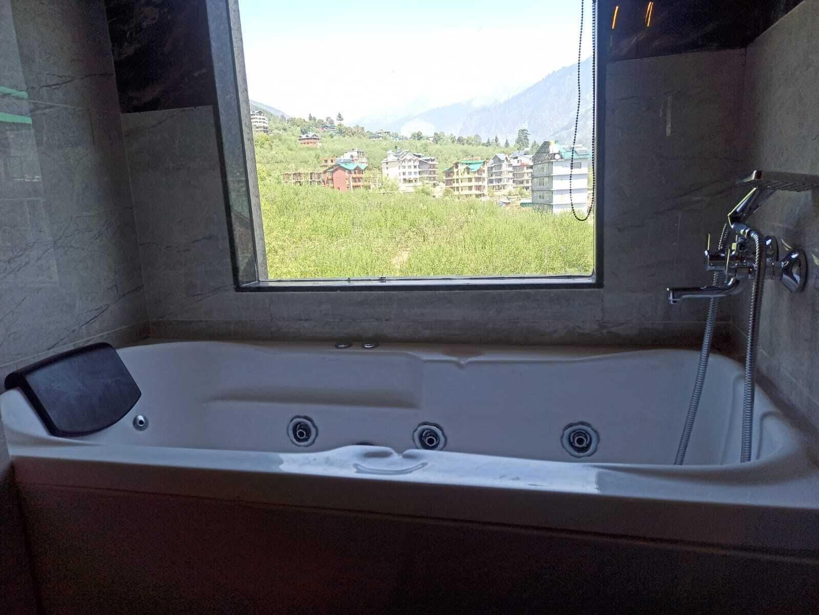 A bathroom with a bathtub, a window, and a shower.