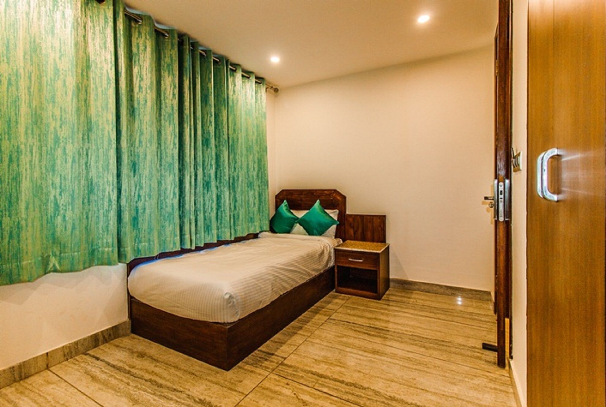 Un dormitorio con cama, mesita de noche y puerta de madera.