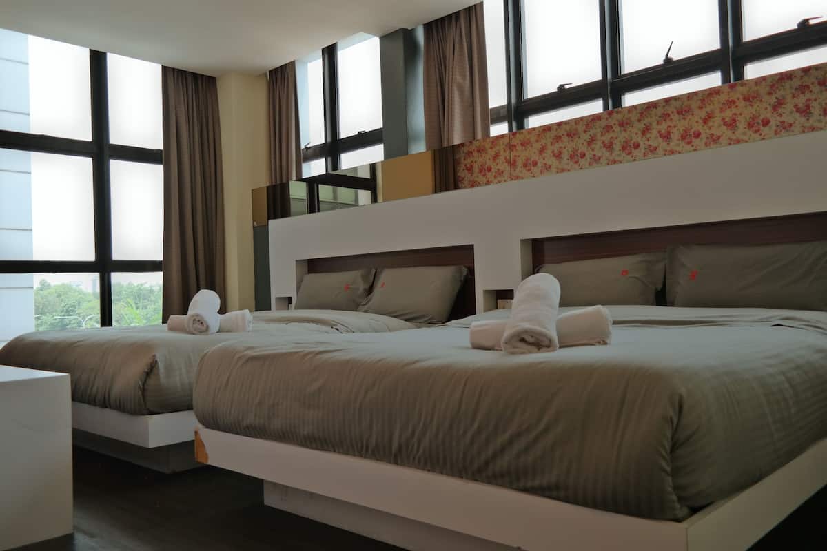 Habitación de hotel con dos camas, ventanas amplias y un balcón.
