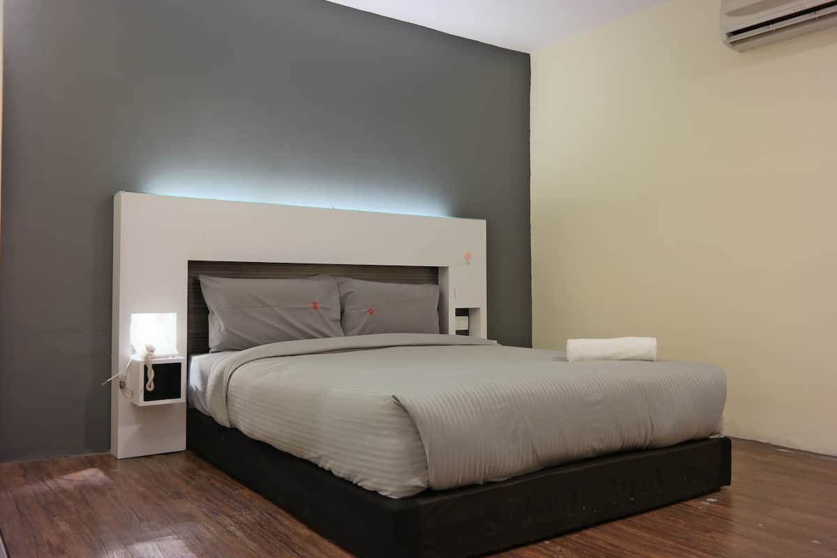 Un dormitorio moderno con cama, mesita de noche y aire acondicionado instalado en la pared.