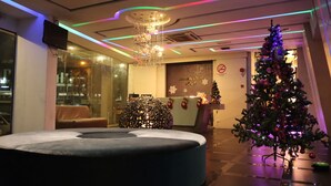 Un hall de hotel con un árbol de Navidad, una zona de estar circular y una recepción.