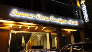 Exterior del Hotel Boutique Summer Oscar con un llamativo letrero iluminado.