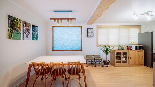 A compact living space with a dining area, kitchen, and a large window with blinds.