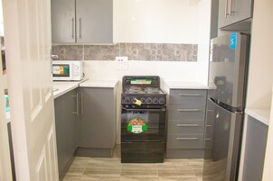 Full-size fridge, microwave, cleaning supplies, dining tables