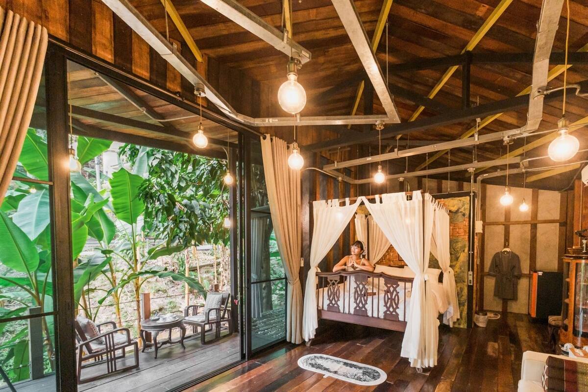 Una habitación con techo de madera, ventanas amplias y una cama con dosel.