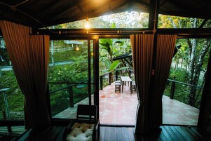 Un espacio de estar techado al aire libre con vista a un jardín exuberante y una terraza de madera.