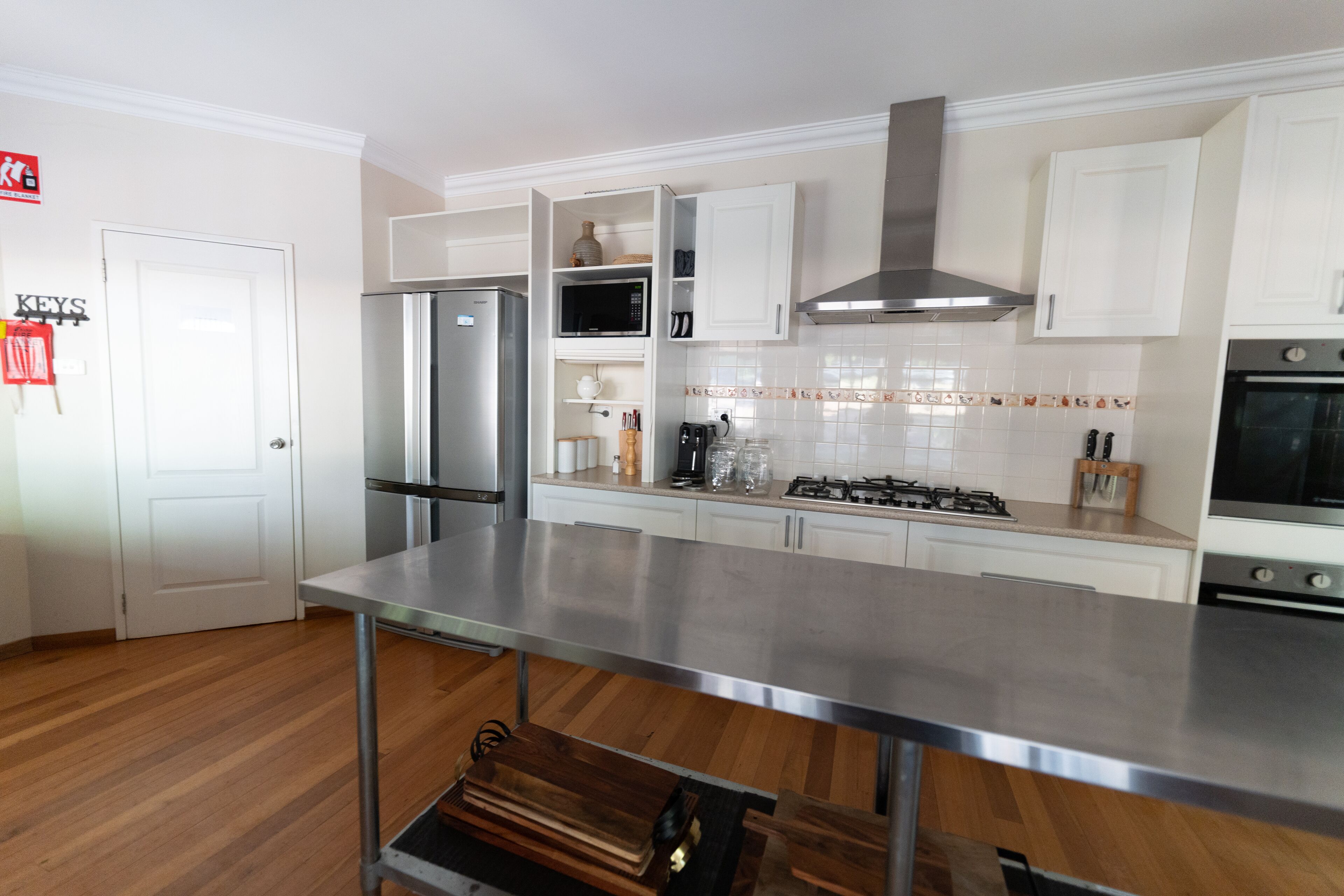 A modern kitchen with white cabinets, stainless steel appliances, and a wooden floor.