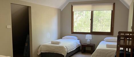 A bedroom with two beds, a window, and a wooden floor.