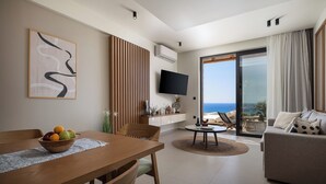 Una sala de estar moderna con una mesa de comedor, un sofá, un televisor y un balcón con vistas al mar.