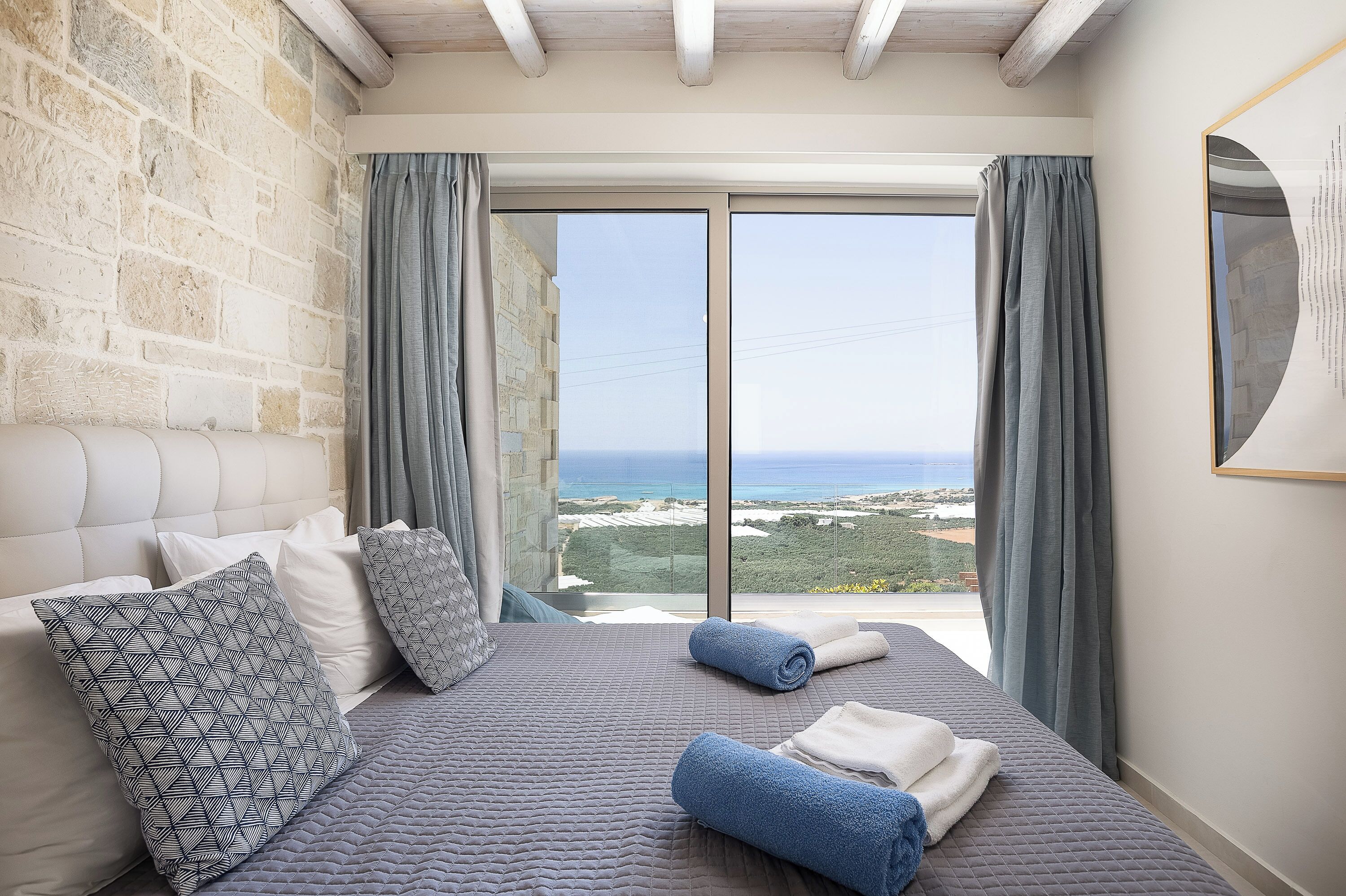 Un dormitorio con una cama grande, una pared de piedra y vistas al mar.