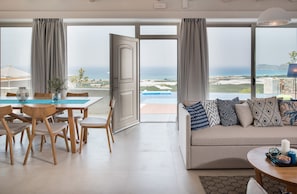 Un salon moderne doté d’une grande porte-fenêtre coulissante donnant sur un balcon avec vue sur la mer.