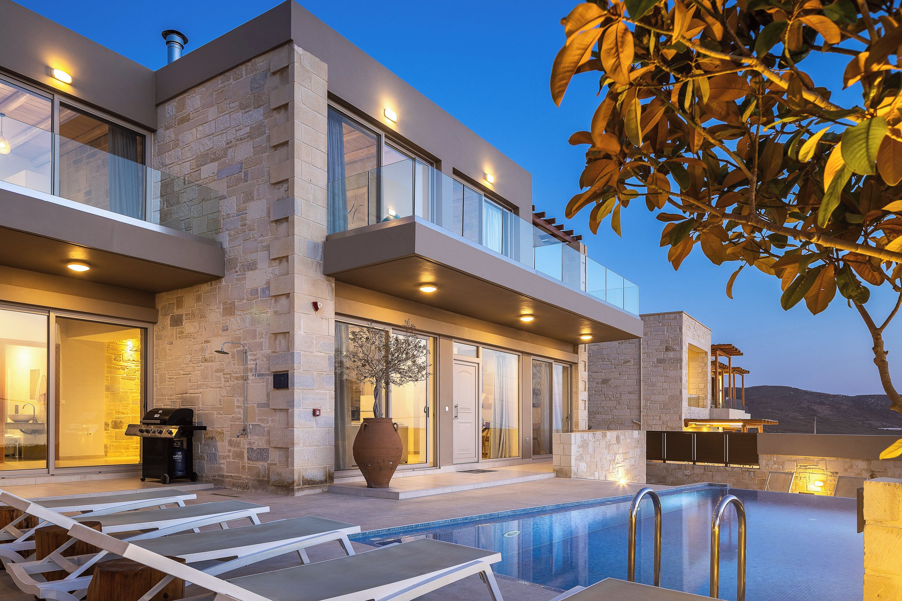 Une maison moderne dotée d’une piscine, d’un espace salon extérieur et d’un coin barbecue.