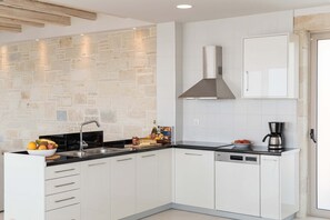 A modern kitchen with white cabinets, a stone backsplash, a stainless steel range hood, and a dishwasher. - Villa Galatia I Free*heated pool, ideal for groups (Kissamos)