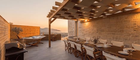 Un espacio de comedor al aire libre con una pérgola, un muro de piedra y vistas al paisaje.