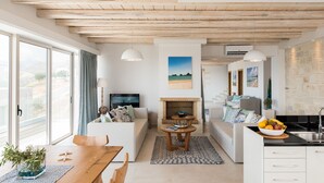 A modern living room with a fireplace, seating area, and a kitchen with a sink.