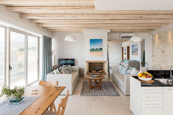 A modern living room with a fireplace, seating area, and a kitchen with a sink. - Villa Galatia I Free*heated pool, ideal for groups (Kissamos)