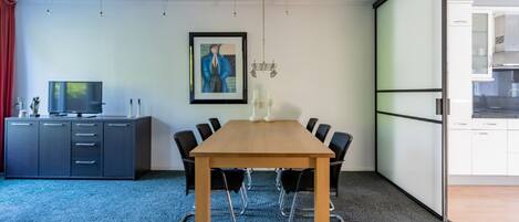 A conference room with a long table, black chairs, a grey cabinet, and a framed picture on the wall.