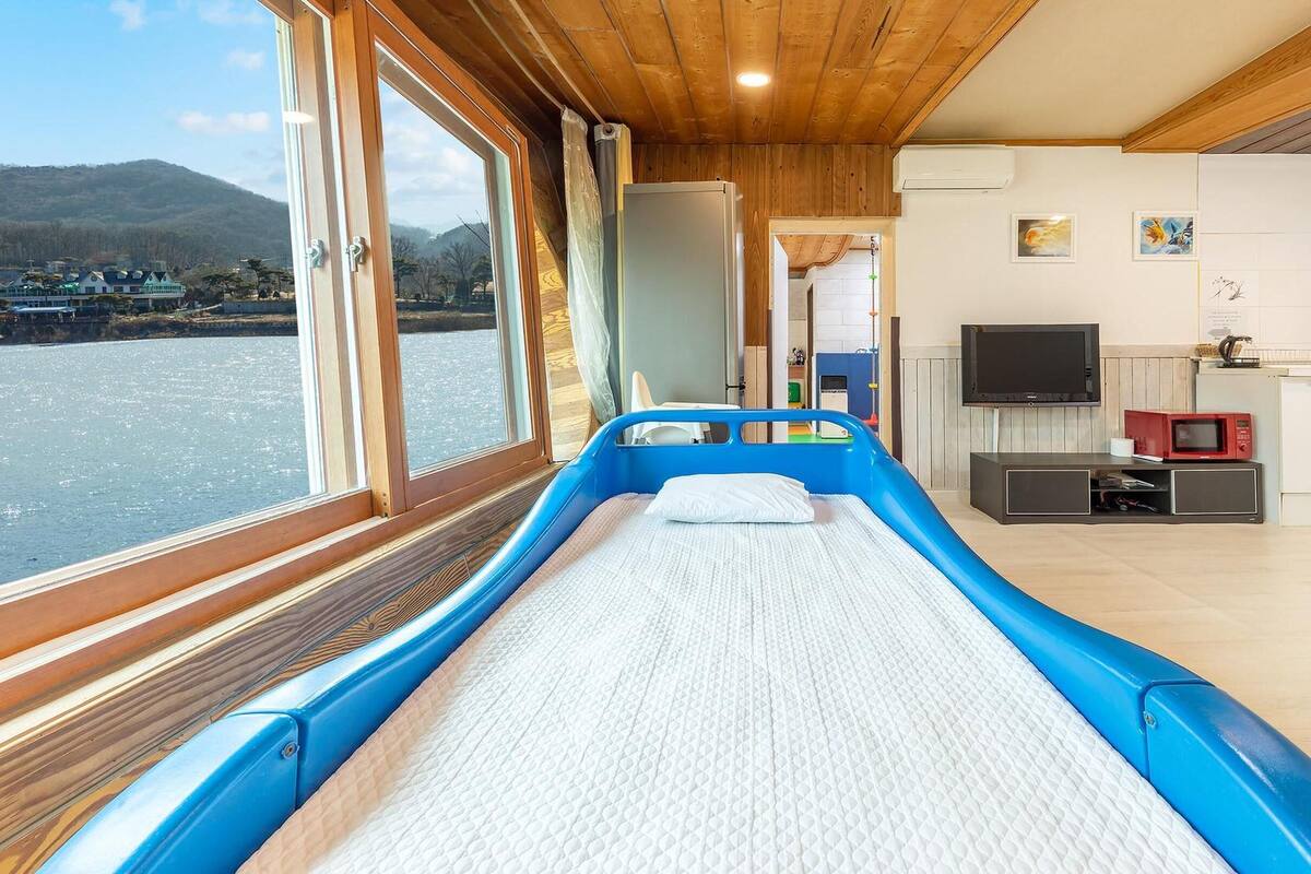 A room with a bed, a TV, a microwave, and a view of a body of water.