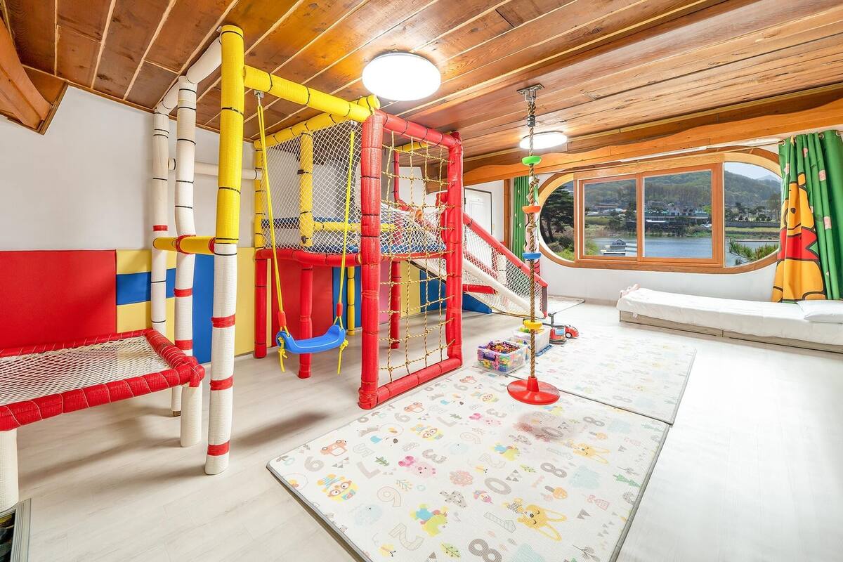 A play area with a climbing structure, a slide, and a small bed.