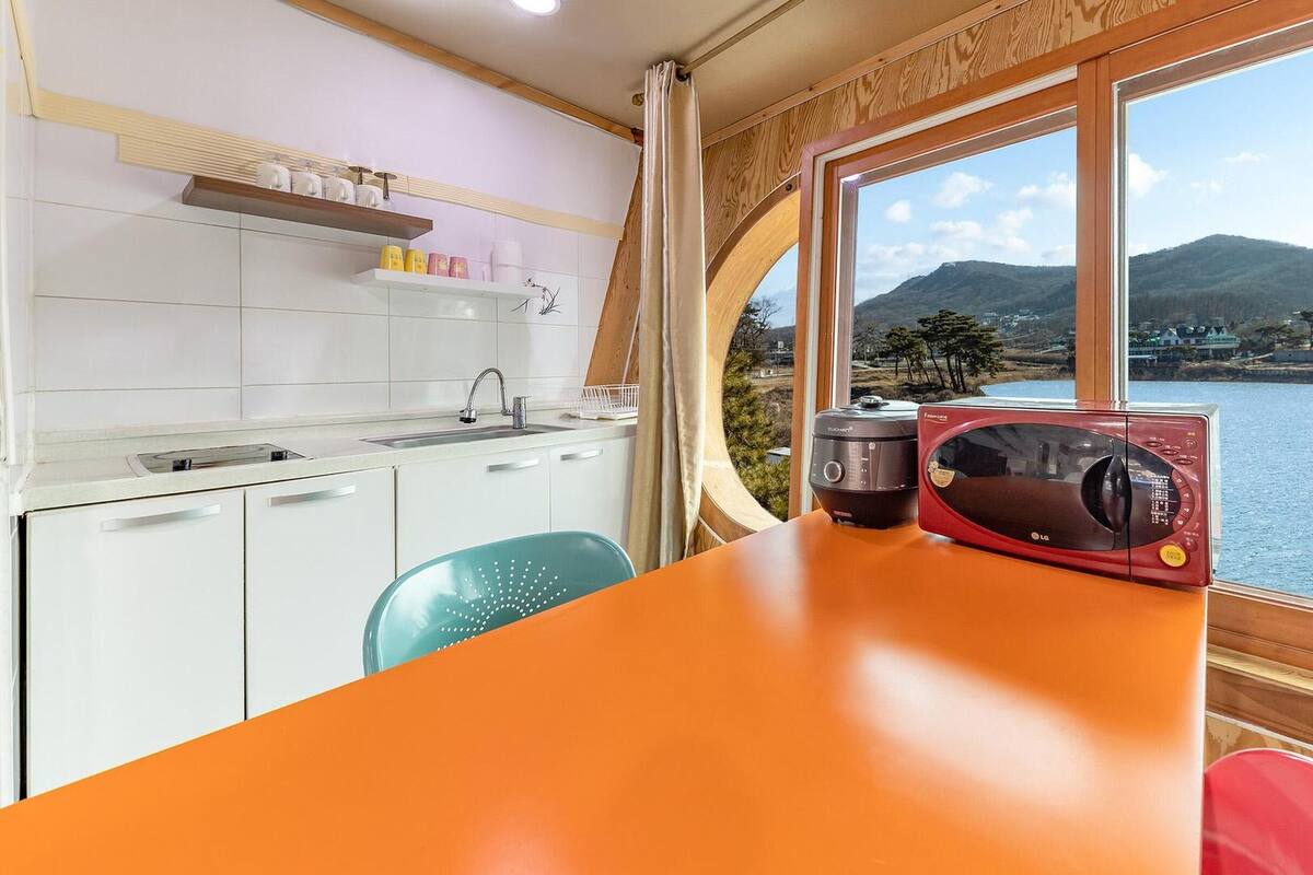 A kitchen with a view of a lake and mountains, a microwave, and a sink.