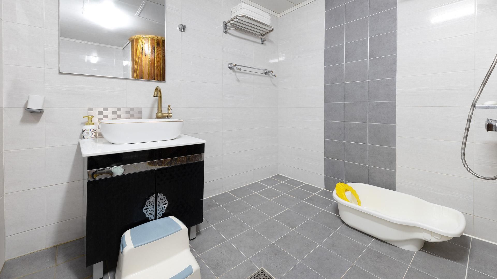 A modern bathroom with a white sink, black vanity, and a white toilet.