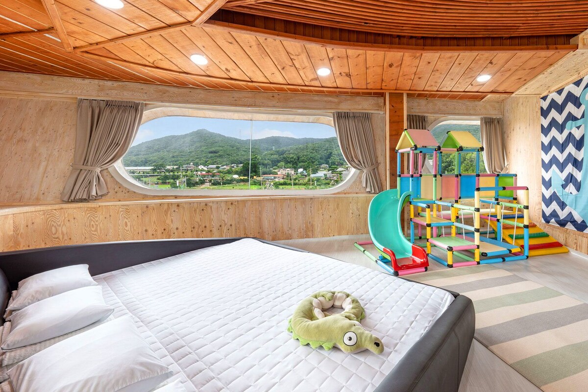 Un dormitorio con cama, vista a un paisaje montañoso, zona de juegos y pared con diseño en chevron.