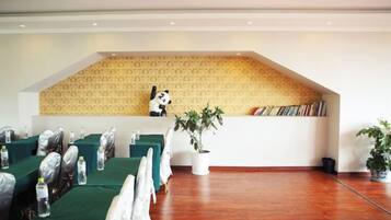 A conference room with tables set up for a meeting, a bookshelf with books, and a panda statue on a shelf.