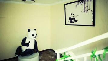 A room with a white staircase, a panda sculpture, and a framed picture on the wall.