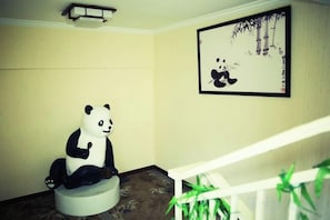 A room with a white staircase, a panda sculpture, and a framed picture on the wall.