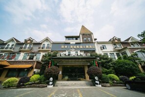A hotel entrance with a traditional architectural style, featuring a central tower and multiple balconies.