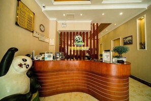 A reception desk with a panda statue, a clock, and framed certificates on the wall. - Qingcheng Panda Hotel (Dujiangyan)