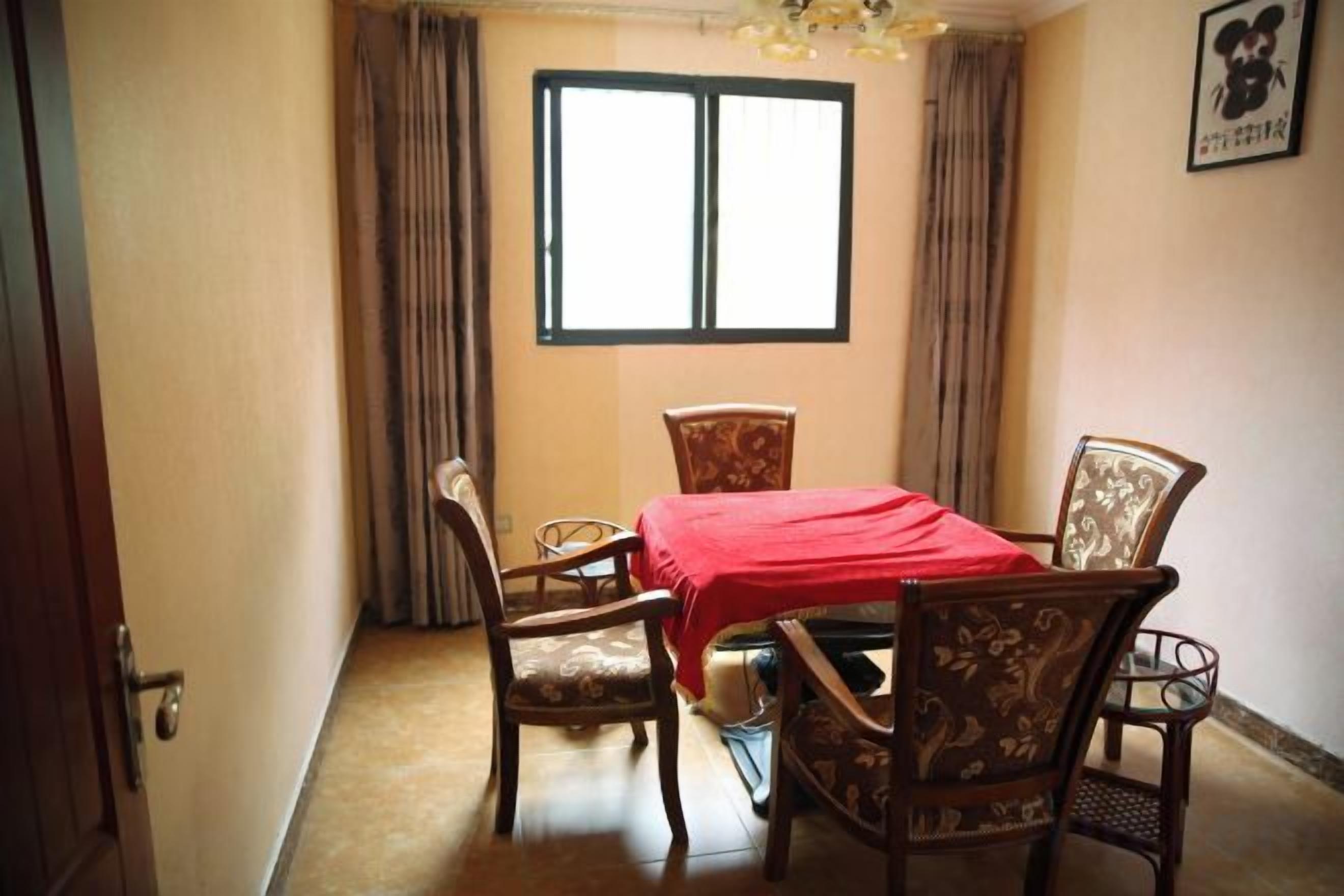 Una habitación con cama, una mesa con sillas, un ventanal y cortinas.