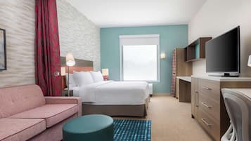 Une chambre d’hôtel avec un lit, un canapé, un bureau avec une télévision, une lampe et une fenêtre donnant sur un paysage agréable.