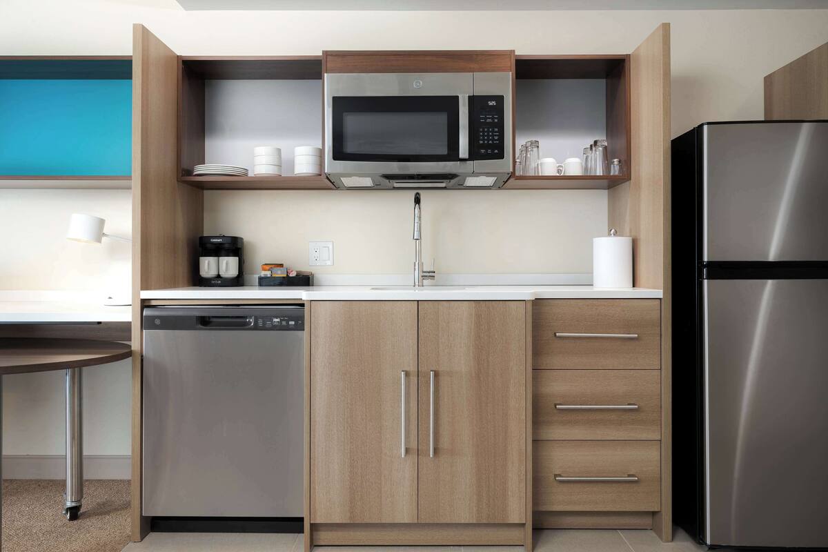 A modern kitchen with a built-in microwave, stainless steel refrigerator, and a dishwasher.