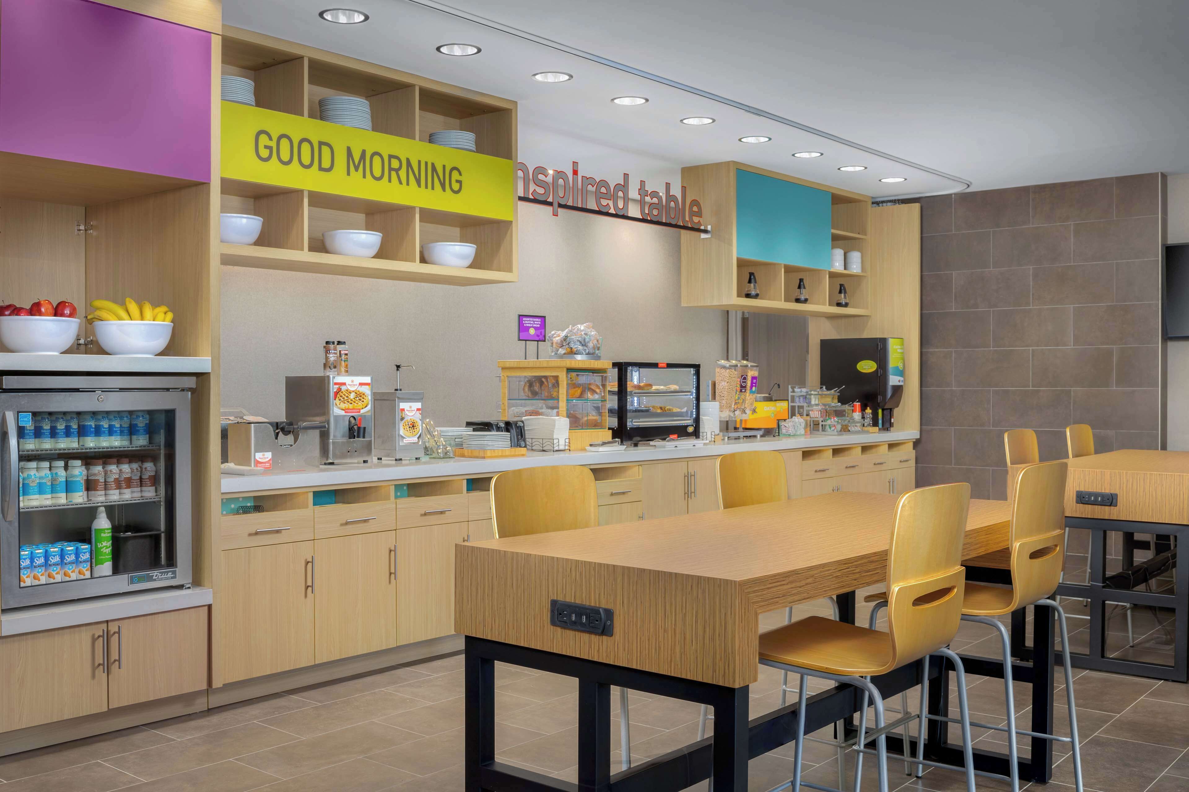 Un área de desayuno moderna con un cartel que dice 'Good Morning', una estación de autoservicio y un cartel que dice 'Inspired Table'.