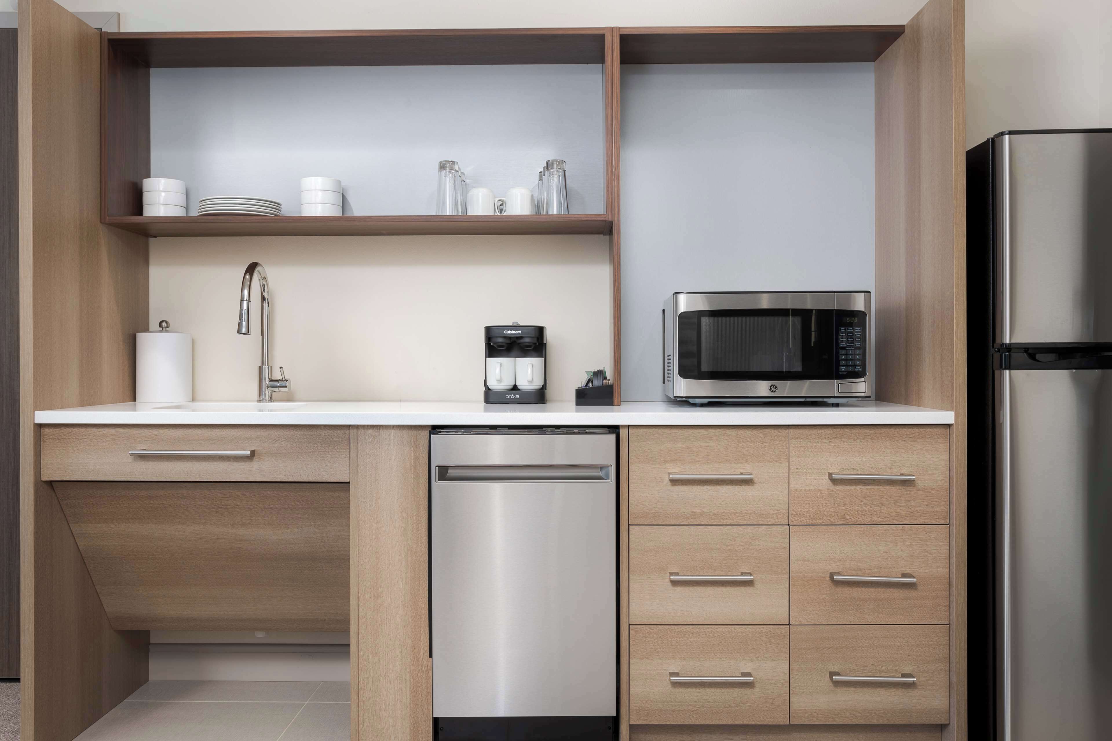 A modern kitchen with a dishwasher, microwave, and refrigerator.