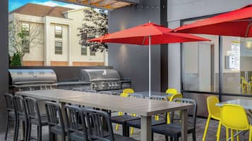 Relax outdoors with a long table and comfortable seating, surrounded by a glass wall offering views of the surrounding area.