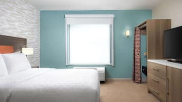 Habitación de hotel con cama, televisión, ventana con cortinas y un calentador de pared.