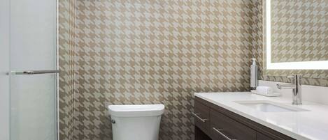 A bathroom with a patterned wall, a toilet, a sink, and a mirror.