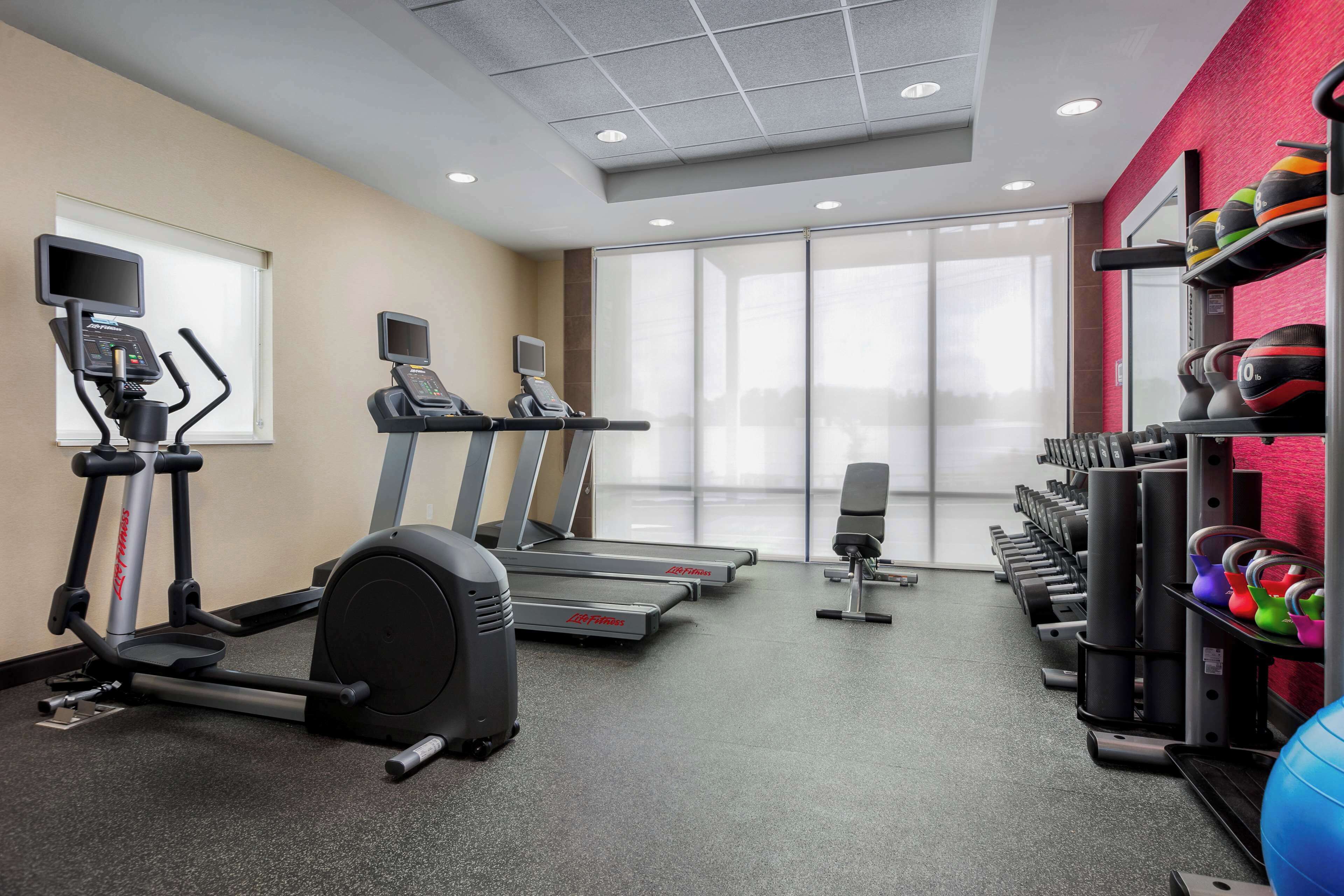 A gym with treadmills, elliptical machines, and free weights.