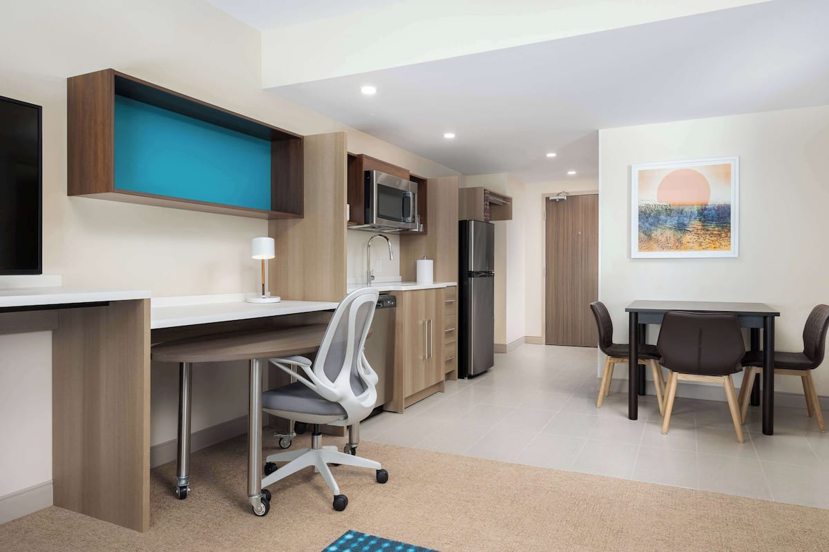 A modern kitchen with a built-in microwave, refrigerator, and a dining area with a table and chairs.