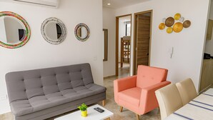 A living room with a grey sofa, a white coffee table, a pink armchair, and a beige sofa. There are three wall mirrors and a decorative wall piece. - Exclusive Apartament In El Rodadero -vita 945 no69 (Gaira)