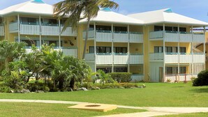 Un hotel de varios pisos con balcones, un césped bien cuidado y una palmera.