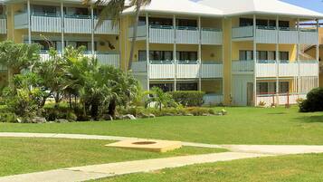 A multi-story hotel with balconies, a well-maintained lawn, and a palm tree.